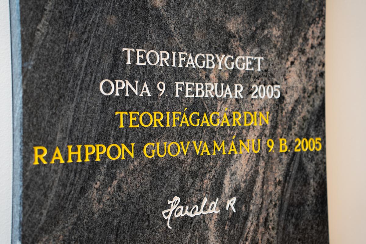 En stentavle med innskripsjonen: TEORIFAGBYGGET OPNA 9 FEBRUAR 2005 TEORIFAGAGARDIN RAHPPON GUOVVAMANU 9 B. 2005  Harald R